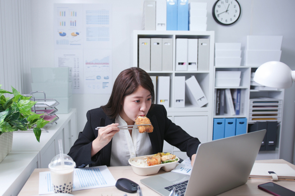 woman binge eating on her desk while working